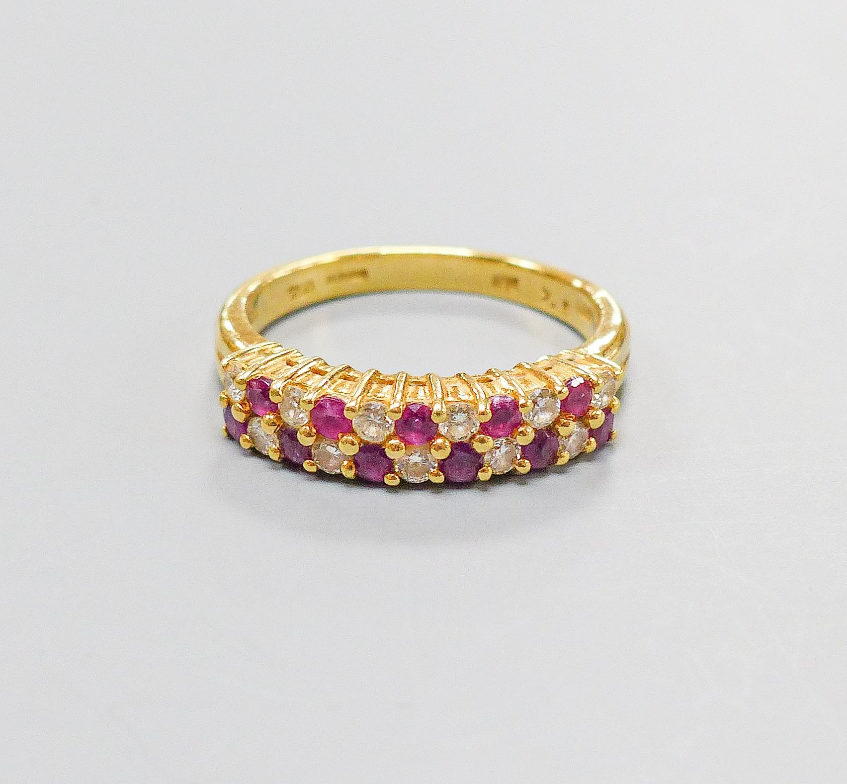 A modern 18ct gold, ruby and diamond set two row half hoop ring, size O, gross 5.3 grams.